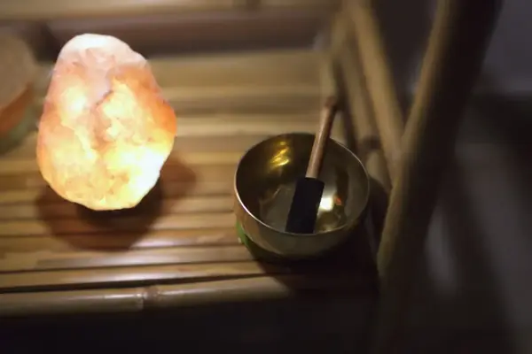 Lámpara de sal encendida y cuenco tibetano en un rincón de calma de Quiroesencia, Granada